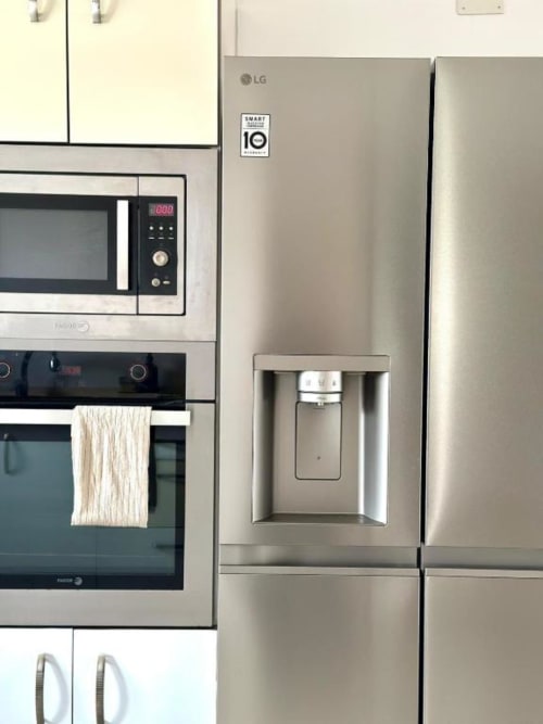 Cocina moderna en acero inoxidable con refrigerador LG, microondas y horno en Villa Faro de Barrosa Home, Hozanejos