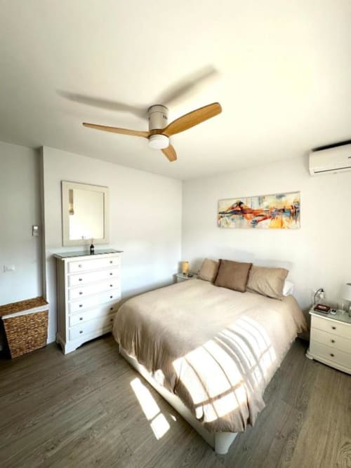 Dormitorio moderno en villa Barrosa Home en Hozanejos con cama queen, ventilador de techo, cómoda blanca y vista al jardín