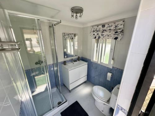 Baño moderno en Villa Faro de Barrosa Home con ducha, lavabo, inodoro y acentos en azulejos azules