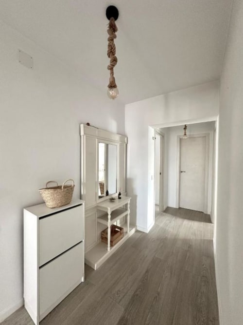 Pasillo moderno en Villa Faro de Barrosa Home con mobiliario blanco, espejo, lámpara colgante de cuerda y vistas al jardín en Hozanejos