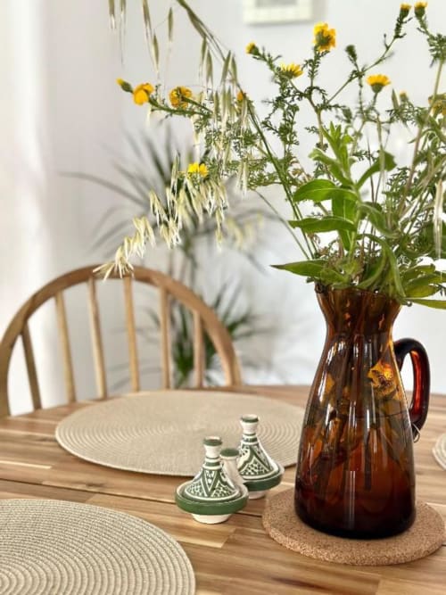 Comedor de la villa Barrosa Home con mesa, flores amarillas en jarra ámbar, cerámicas decorativas y vista al jardín, Hozanejos