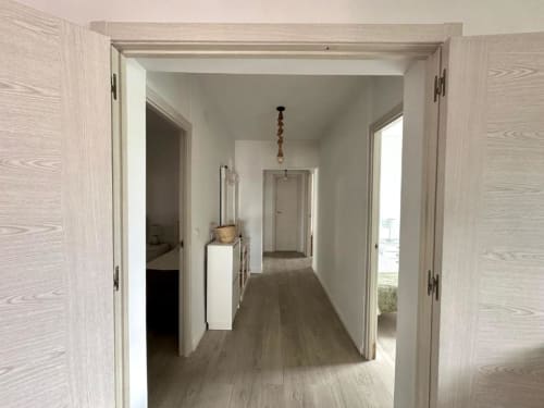 Pasillo moderno en Villa Faro de Barrosa Home, Hozanejos, con puertas y suelo de madera clara que conducen a múltiples habitaciones