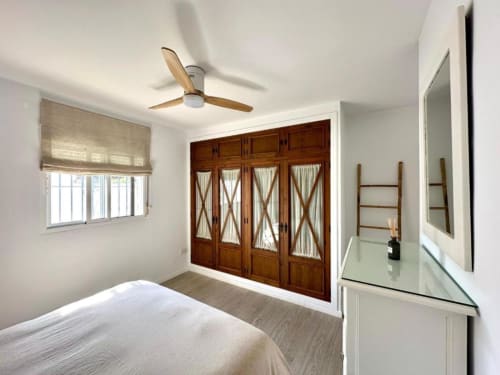Luminosa habitación en Villa Faro de Barrosa Home con armario de madera, ventilador de techo y ventana con vistas al jardín