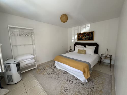 Chambre lumineuse avec lit queen-size, plaid doré, chevets noirs, penderie blanche et luminaire terracotta à Domaine de Bize