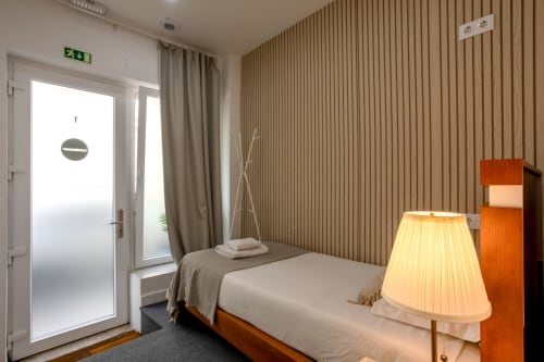 Lisbon Poets Inn hostel suite bedroom with wooden bed, warm lamp, and private entrance door