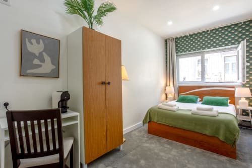Modern double bedroom at Lisbon Poets Inn with green accents, wooden wardrobe, desk, and city views
