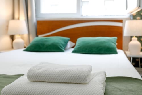 Lisbon Poets Inn suite bedroom with orange headboard, green pillows, white bedding, and folded towels