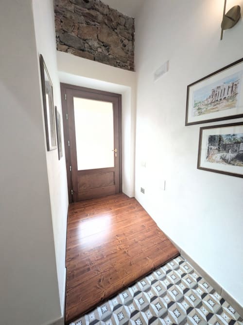 Ingresso dell'Albergo Al Cinghiale con porta in legno, pavimento a mattonelle decorate e quadri alle pareti