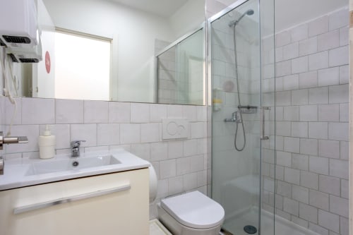 Modern bathroom with white subway tiles, vanity sink, mirror, private shower enclosure at Lisbon Poets Inn hostel