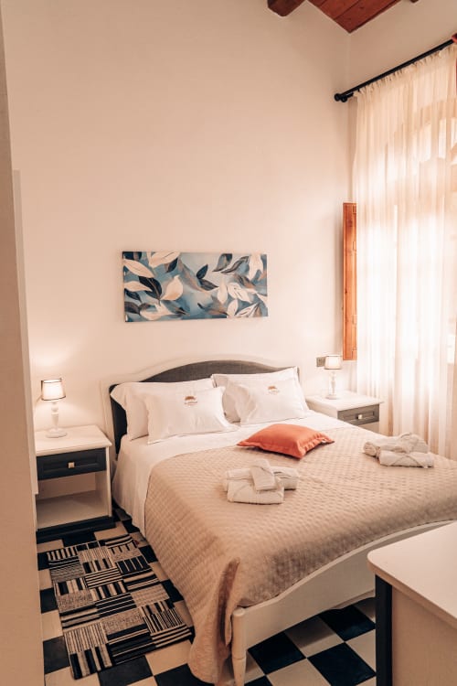 Camera moderna e accessibile all'Albergo Al Cinghiale di Guspini con letto matrimoniale, biancheria color crema e cuscino arancione