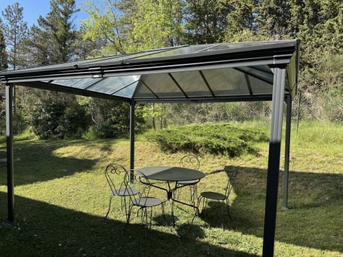 Pergola contemporaine avec mobilier de repas ombrageanT un jardin herbeux du Domaine de Bize, Mirepoix