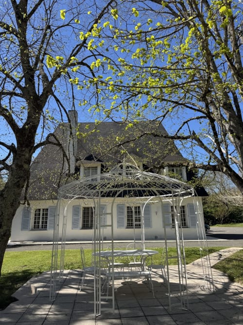 Pavillon blanc en métal dans le jardin avec arbres en fleurs du manoir Domaine de Bize Mirepoix, Ariège
