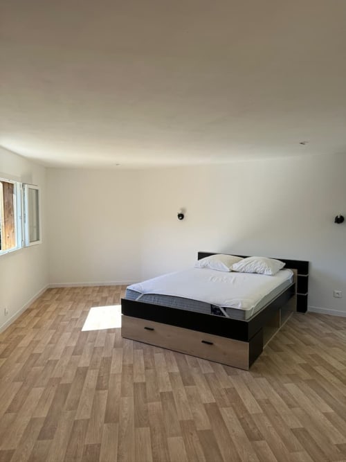 Chambre moderne avec lit à cadre noir, literie blanche, parquet et fenêtres à la villa Les Villas d'A Storia
