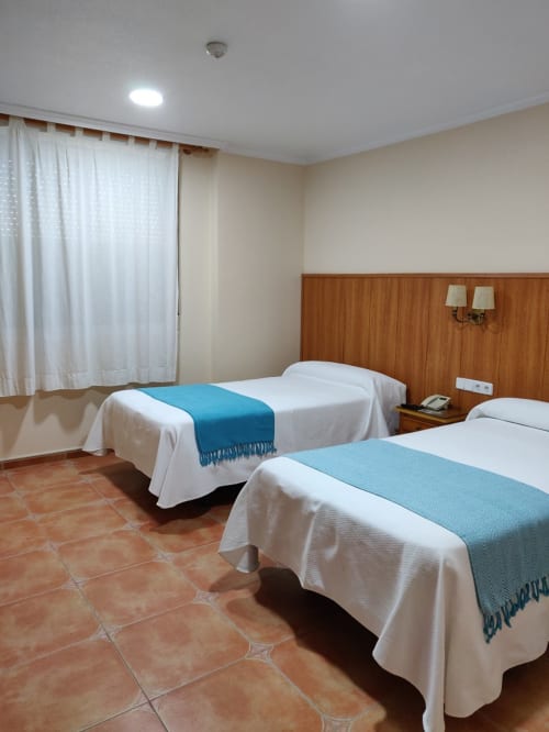 Habitación doble en Hotel La Posada con dos camas individuales, cabecero de madera, suelos de barro y comodidades modernas