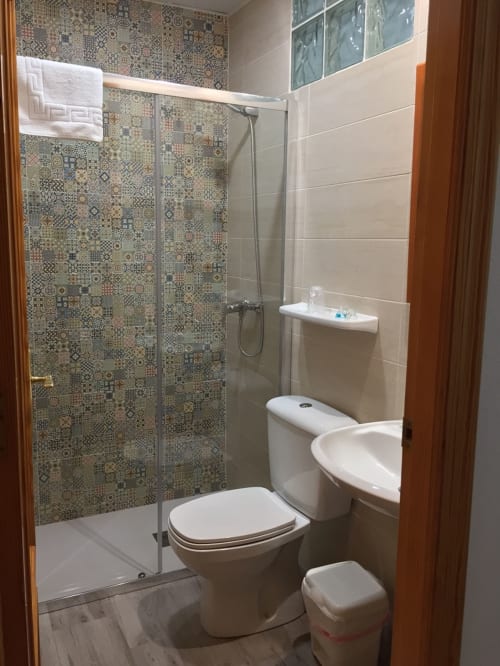 Baño moderno en Hotel La Posada con ducha de azulejos decorativos, accesorios blancos y paredes beige