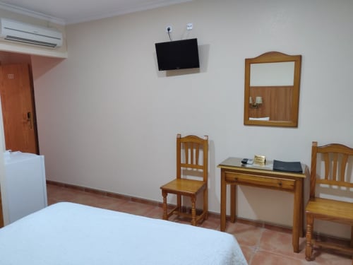 Habitación doble de Hotel La Posada con muebles de madera, TV de pantalla plana, escritorio, espejo y aire acondicionado en España