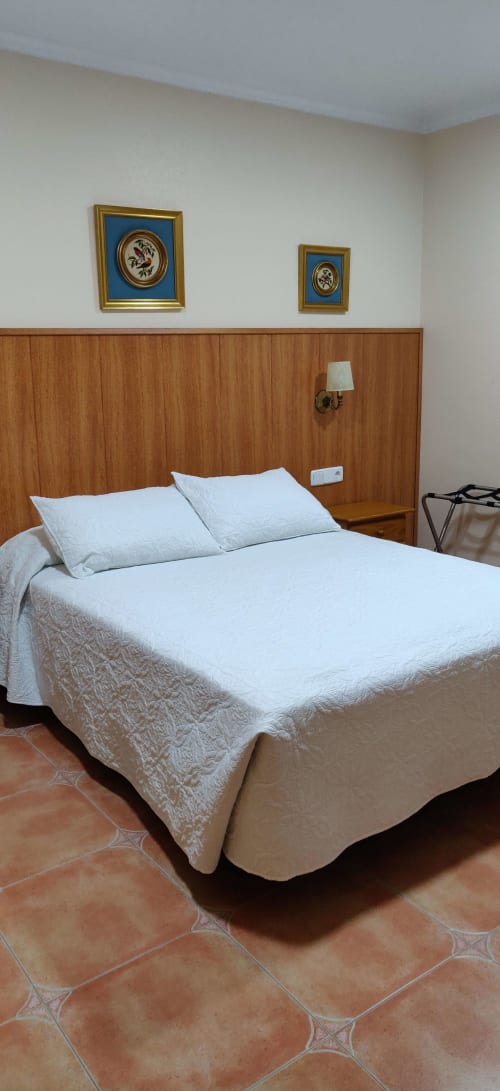 Dormitorio doble con ropa de cama blanca y cabecero de madera en Hotel La Posada, España