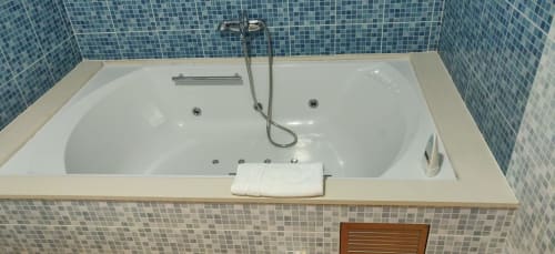 Bañera de hidromasaje del Hotel La Posada con azulejos de mosaico azul y ducha manual en habitación de hotel español