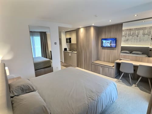 Chambre moderne avec lit, bureau, TV et balcon vue lac aux Résidences Attica St-Sulpice