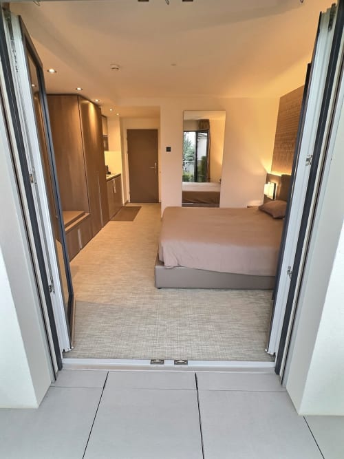 Chambre studio moderne aux Résidences St-Sulpice Attica avec vue sur le lac, lit, penderie et décoration contemporaine