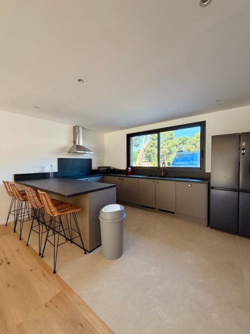 Cuisine moderne et espace repas à la Villa Arasu des Villas d'A Storia, Porto-Vecchio, avec îlot central et vue sur la piscine