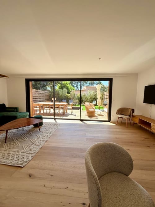 Villa moderne avec salon aux planchers de bois, mobilier contemporain et portes-fenêtres coulissantes donnant sur le patio aux Villas