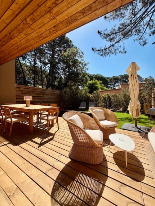 Terrasse Villa Arasu avec terrasse en bois, fauteuils en rotin, table à manger, parasol et pelouse soignée à Porto-Vecchio