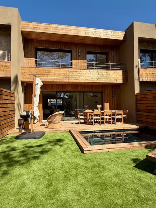 Cour moderne de la villa aux Villas d'A Storia à Porto-Vecchio avec terrasse en bois, piscine privée, coin repas et jardins entretenus