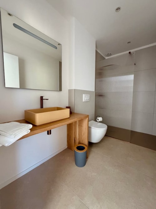 Salle de bain moderne de la Villa Arasu aux Villas d'A Storia, Porto-Vecchio, avec meuble vasque en bois et douche à effet pluie