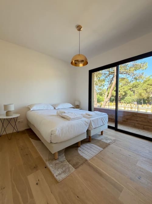 Chambre moderne de la Villa Arasu aux Villas d'A Storia, Porto-Vecchio, avec lit blanc, lustre doré et vues sur