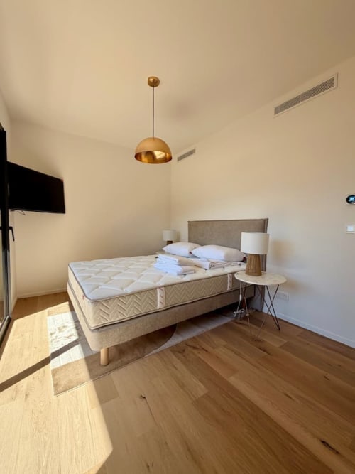 Chambre lumineuse de la Villa Arasu avec lit queen-size, luminaire doré, parquet et équipements modernes aux Villas d'A