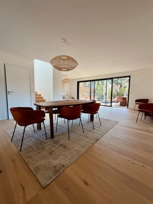 Salle à manger contemporaine avec chaises bordeaux, table en bois et luminaires suspendus tressés à la Villa San Ciprianu, Porto-Vecchio