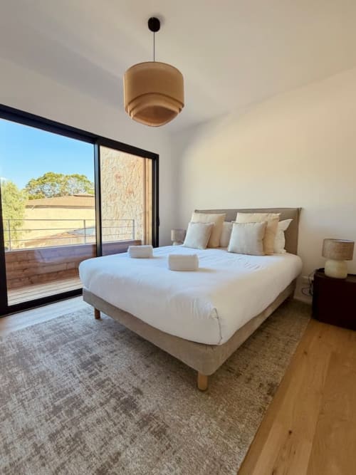 Chambre moderne de la villa Les Villas d'A Storia avec vue sur la piscine, lit blanc, parquets et balcon aménagé