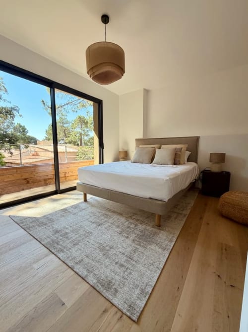 Chambre moderne à la Villa San Ciprianu, Porto-Vecchio, avec lit, vue sur piscine privée par portes vitrées, parquet, et