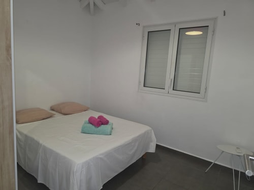 Chambre Villa Spinel avec lit double, serviettes pliées et baie vitrée donnant sur la piscine à Maly Blue Location, Le Moule
