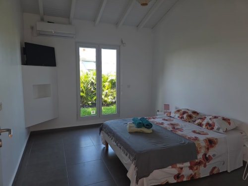 Chambre moderne à la Villa Spinel, Maly Blue Location, avec lit double, téléviseur écran plat, climatisation et portes-fenêtres donnant sur
