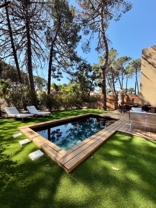 Piscine privée avec terrasse en bois entourée de pelouse verdoyante et de hauts pins à Villa Cala Rossa, Les Villas d'A Storia
