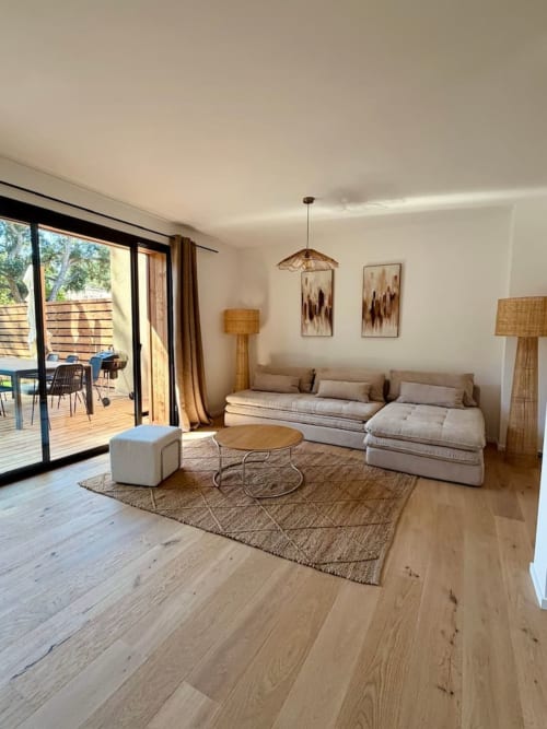 Salon moderne de la villa aux Villas d'A Storia avec canapé sectionnel beige, parquet et accès à la terrasse