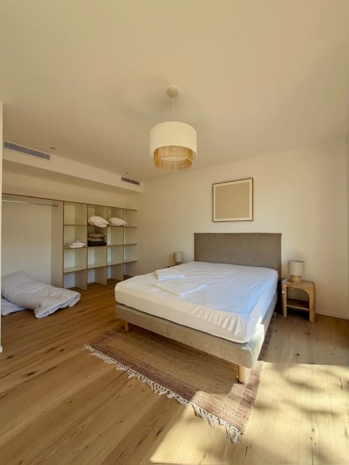 Chambre moderne aux Villas d'A Storia à Porto-Vecchio avec lit queen-size, parquet, luminaire suspendu et rangements intégrés