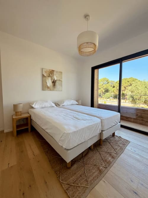 Deux lits jumeaux dans la chambre lumineuse de la villa avec portes coulissantes donnant sur les arbres, Les Villas d'A Storia, Porto-Vecchio