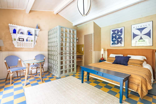 Chambre L'Étang au Moulin de Lassalle à Linxe avec lit orange, banc bleu, carrelage géométrique et décoration nautique