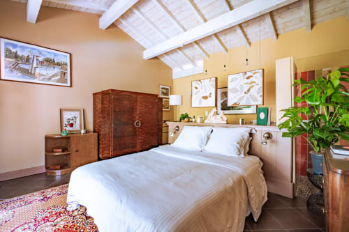Chambre lumineuse au Moulin de Lassalle avec mobilier en bois, poutres blanches au plafond, murs jaunes et plantes tropicales