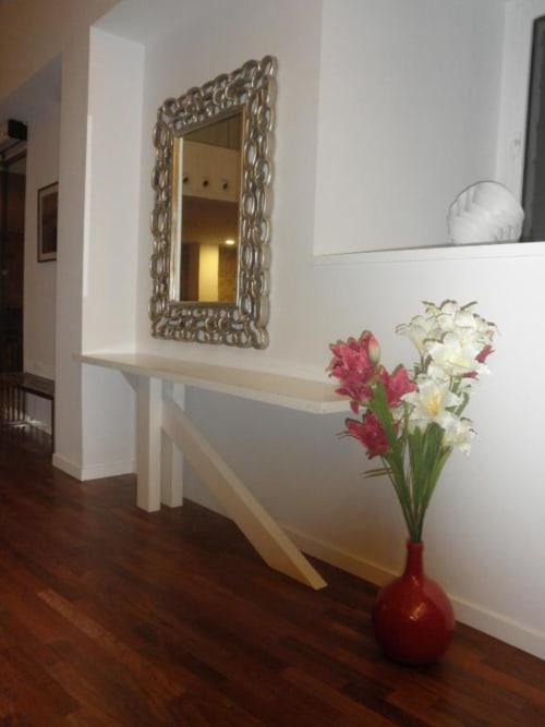 Elegante pasillo del Hostal Doña Blanca con espejo ornamentado, consola blanca y flores frescas en jarrón rojo