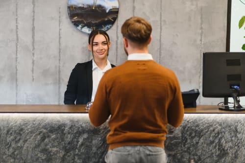 Réceptionniste d'hôtel accueillant un client à la réception de RJD Conciergerie Côte d'Azur à Sainte-Lucie-de-Porto-Vecchio