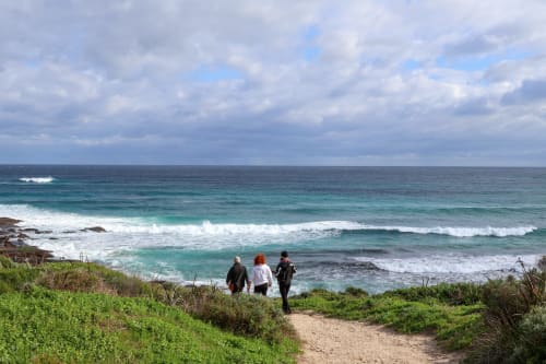 Trois visiteurs marchent sur un sentier côtier surplombant les eaux turquoise près de Sainte-Lucie-de-Porto-Vecchio, Côte d'Azur
