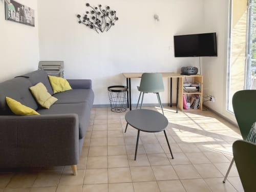 Séjour moderne à LOCADIGNE Digne-les-Bains avec canapé gris, bureau, TV et vue sur les montagnes par les portes-fenêtres