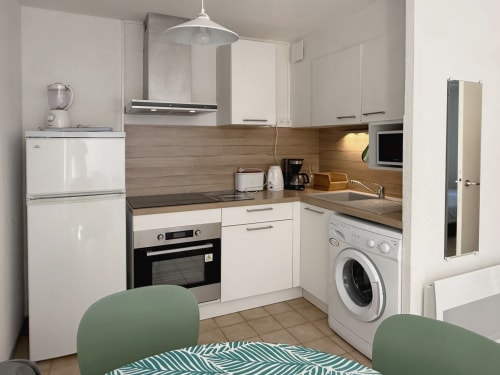 Cuisine moderne avec armoires blanches, crédence en bois et électroménagers de l'appartement Vallon des Sources à Digne-les-Bains