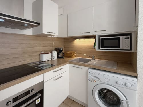Cuisine moderne dans un appartement de Digne-les-Bains avec armoires blanches, comptoirs en bois et électroménagers intégrés