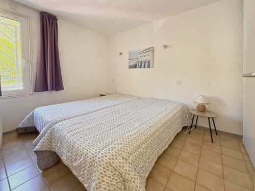 Chambre de l'appartement LOCADIGNE à Digne-les-Bains avec lit double, fenêtre, rideaux violets et table de nuit