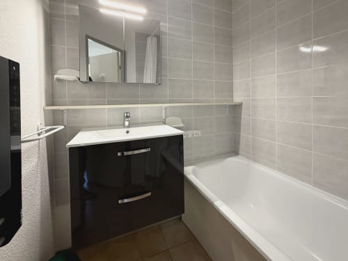 Salle de bain moderne de l'appartement Vallon des Sources à LOCADIGNE, Digne-les-Bains, avec vasque noire, miroir, baignoire et